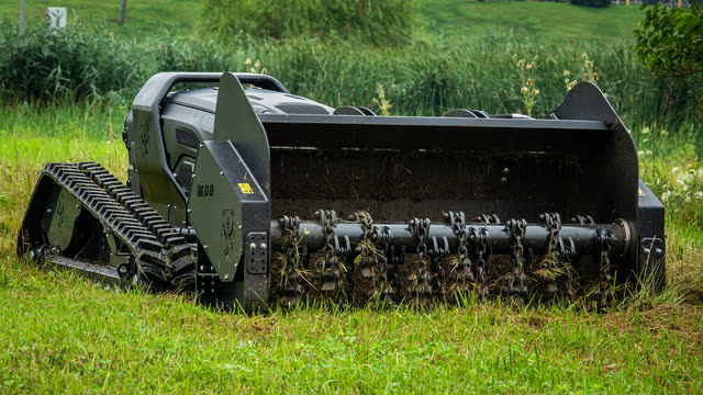 Chain flail head beating a cleared lane through ground cover.